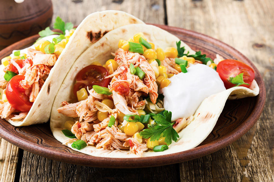 Chicken tacos on a wooden plate.