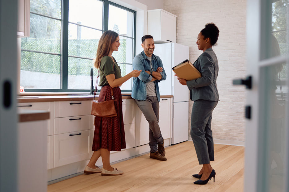 A couple in a nice kitchen talking to a real estate agent.